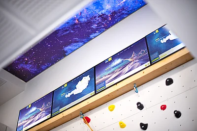 Kletterwand mit Weltraumhimmel und Screens
