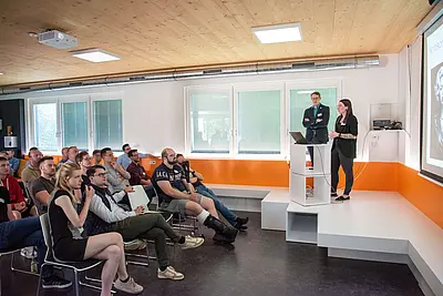 Vortragende auf Bühne und Publikum