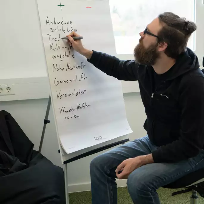 Mann schreibt auf Flipchart