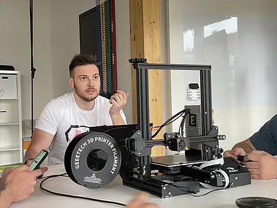 Menschen sitzen um 3D Drucker